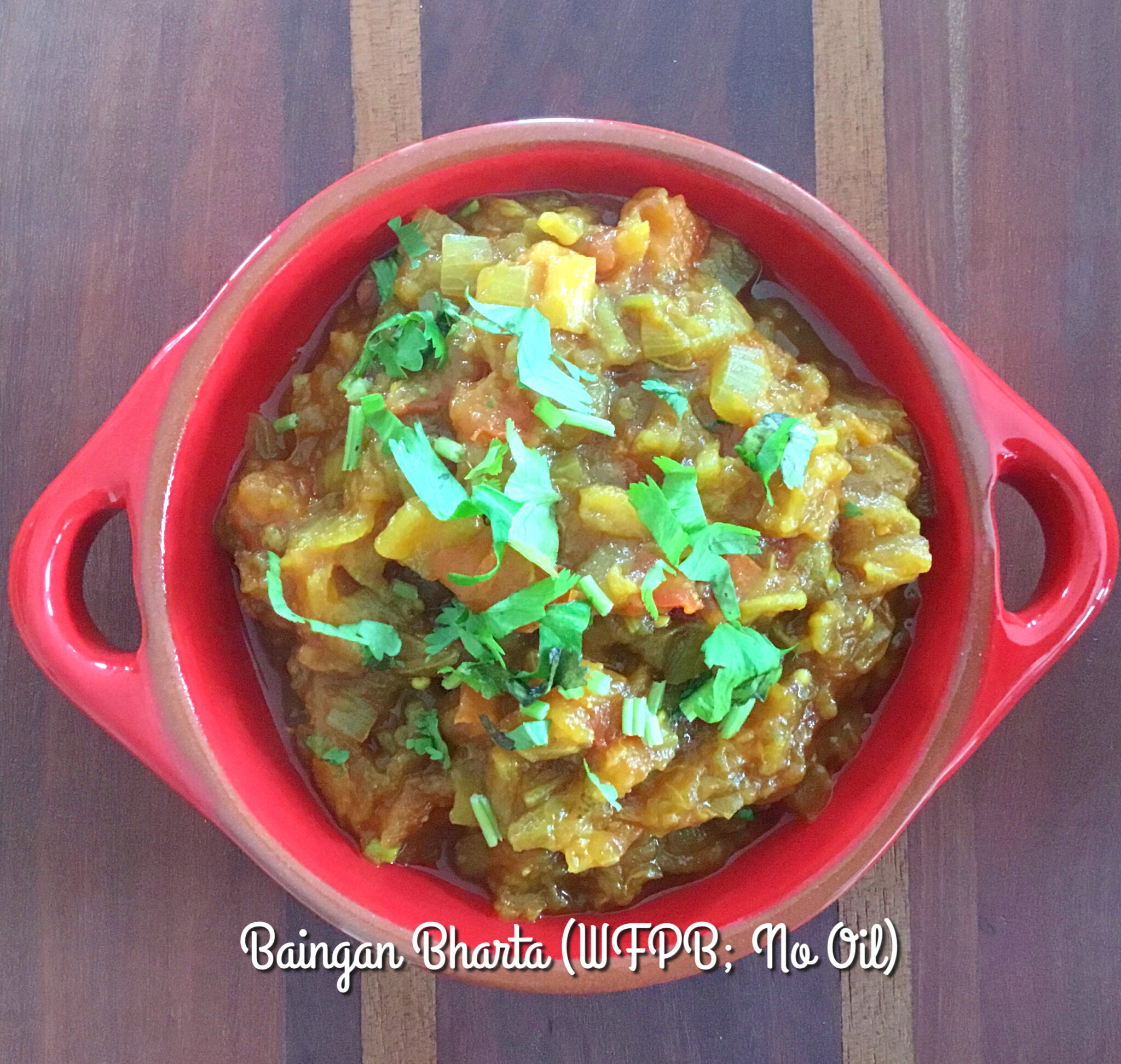 Baingan Bharta WFPB is a Spiced Eggplant Mash in a red serving dish, garnished with green coriander